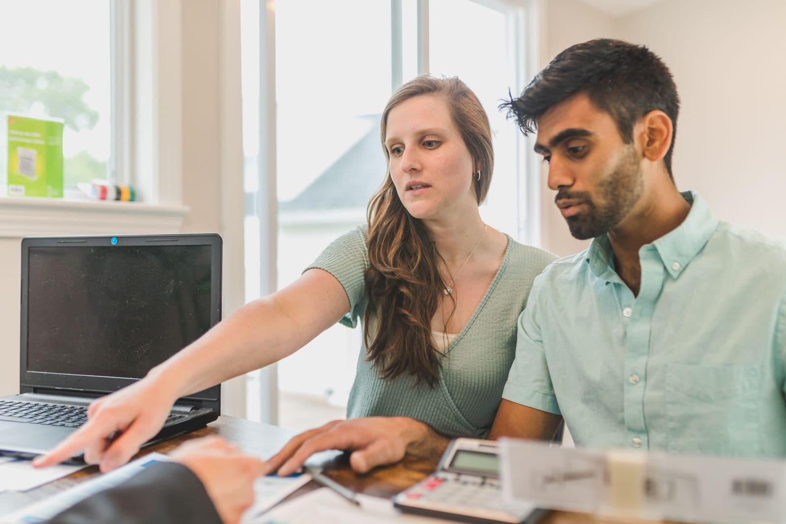 A couple reviewing their options with a counselor at a laptop in a bright room.